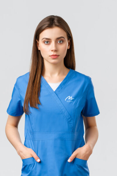 Healthcare workers, prevent virus, insurance and medicine concept. Serious-looking, confident young medical worker, nurse or doctor in blue scrubs hold hands in pockets and looking camera.